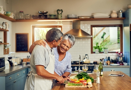 A couple laughs in a kitchen while cooking