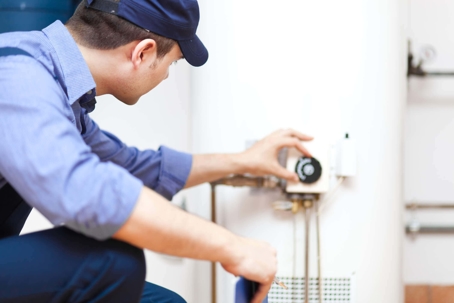 A technician examines a water heater
